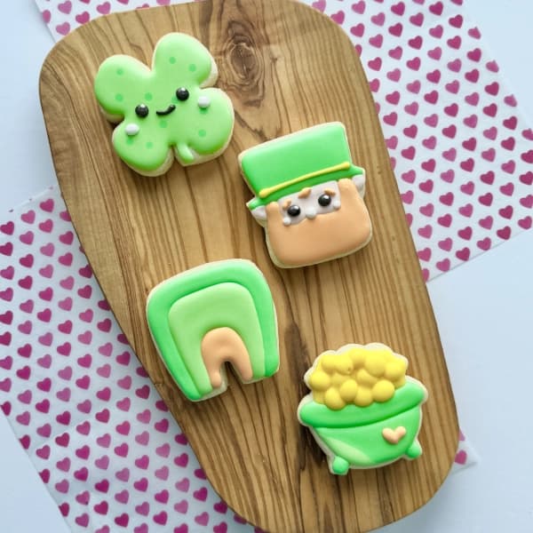 Mini sugar cookies decorated to look like a shamrock, leprechaun, rainbow and pot of gold